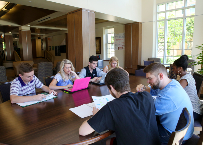 Group of students gathered around a large, wooden table