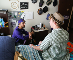 Button takes you to upper division student housing steps. TCU students in dorm talking to each other.